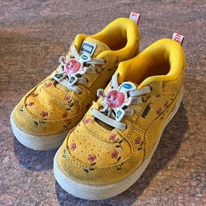 Flowered, yellow puma shoes with flowers on them